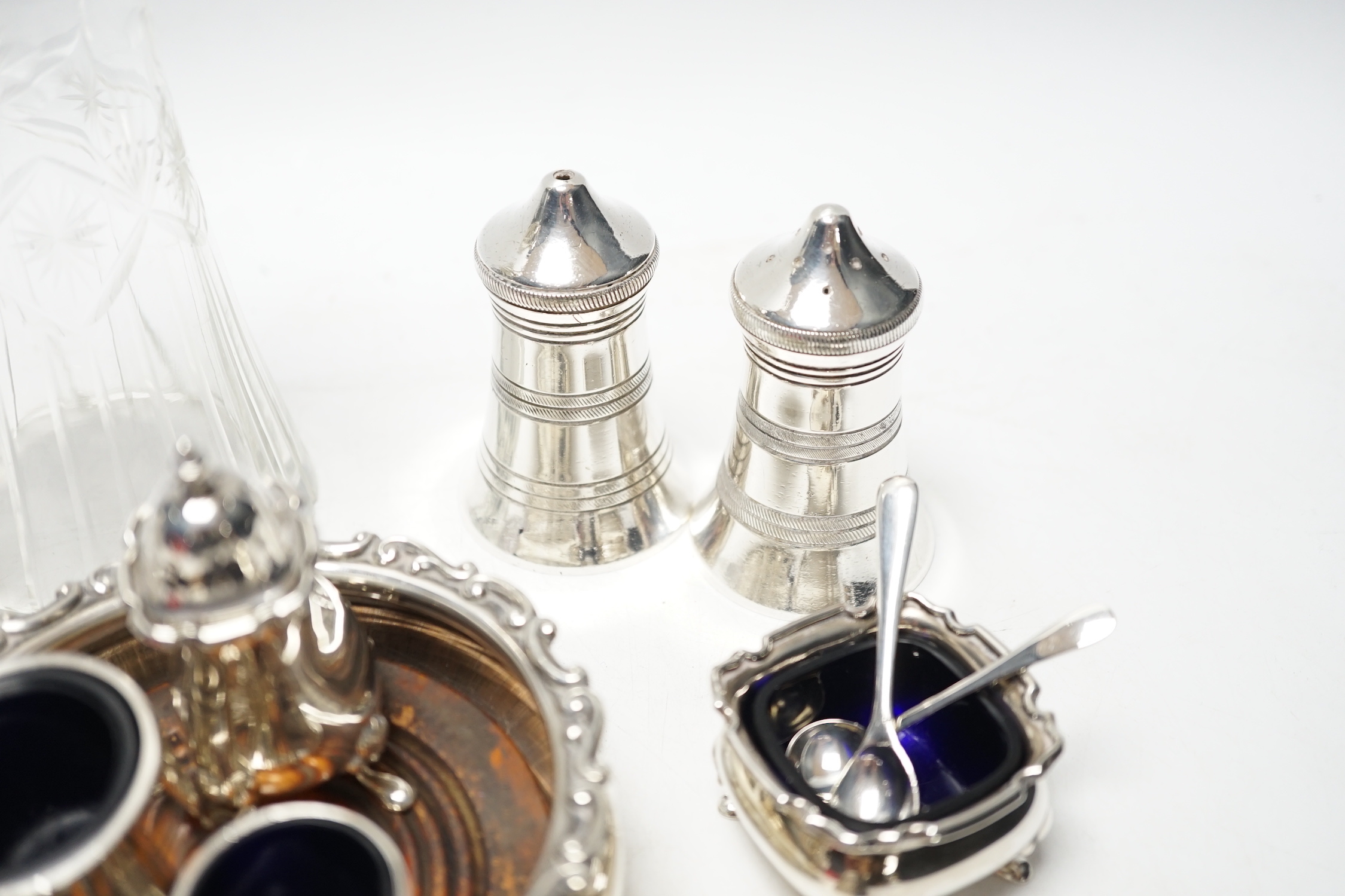 An Edwardian silver wine coaster, William Hutton & Sons, Birmingham, 1903, diameter 10.4cm, a later silver three piece condiment set, a silver mounted glass preserve jar, with a George silver teaspoon and six plated item